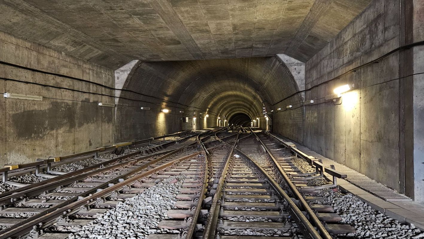 Flersporet jernbane i opplyst betongtunnel med svake kurver og kryssende spor